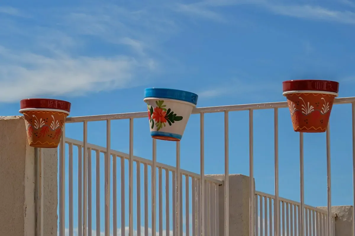 Macetas colgantes de colores en la barandilla de un balcón